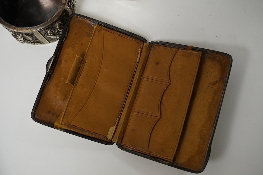 An Edwardian rectangular embossed silver mounted note case, leather lined, Goldsmiths & Silversmiths Co Ltd, London, 1901, 10.3cm, an oval silver tea caddy and cover and an Indian white metal circular box. Condition - po